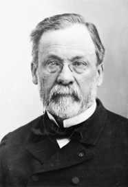 Black and white portrait of an older man with glasses and a beard, wearing a formal coat and bow tie.