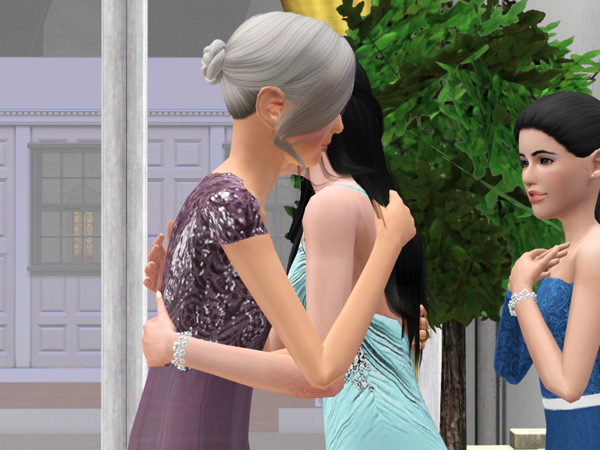 Two women embrace warmly, dressed in elegant attire, while a third woman observes with a smile in a festive setting.