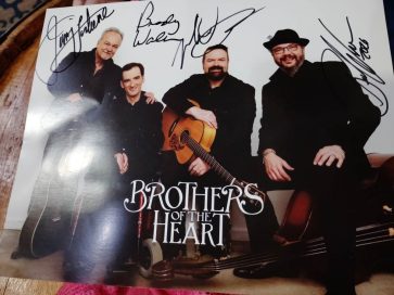 A signed promotional photo of the musical group 'Brothers of the Heart' featuring four members posing with guitars and instruments.