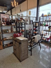 A cozy antique shop interior featuring a wooden display table and various shelves filled with vintage items and home decor.