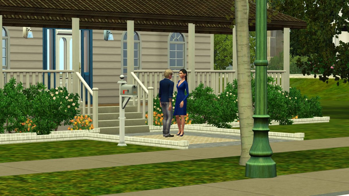 A man and woman are conversing on the sidewalk in front of a house with a porch. The woman is wearing a blue dress and the man is dressed casually. The surrounding area features bushes and flowers, contributing to a suburban atmosphere.